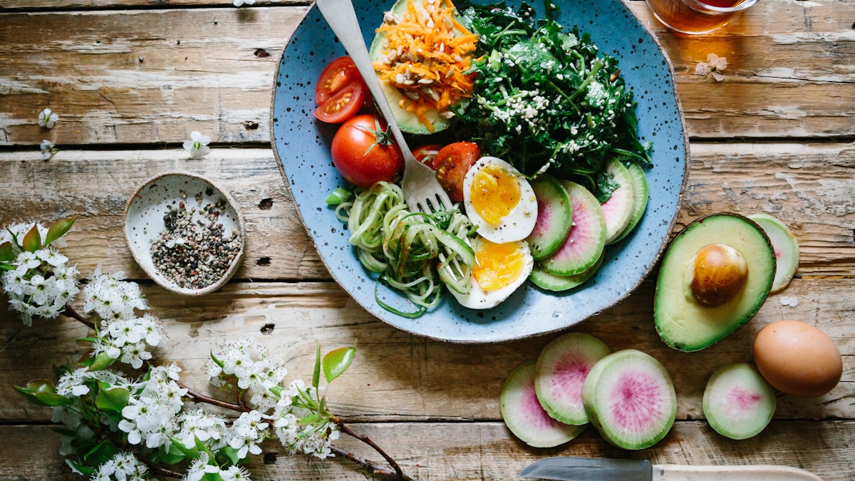 A healthy low-carb meal with zucchini noodles, eggs, avocado, and greens