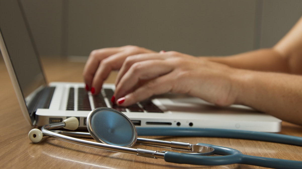 A stethoscope on a desk next to a laptop — representing the behind-the-scenes work of preventive care